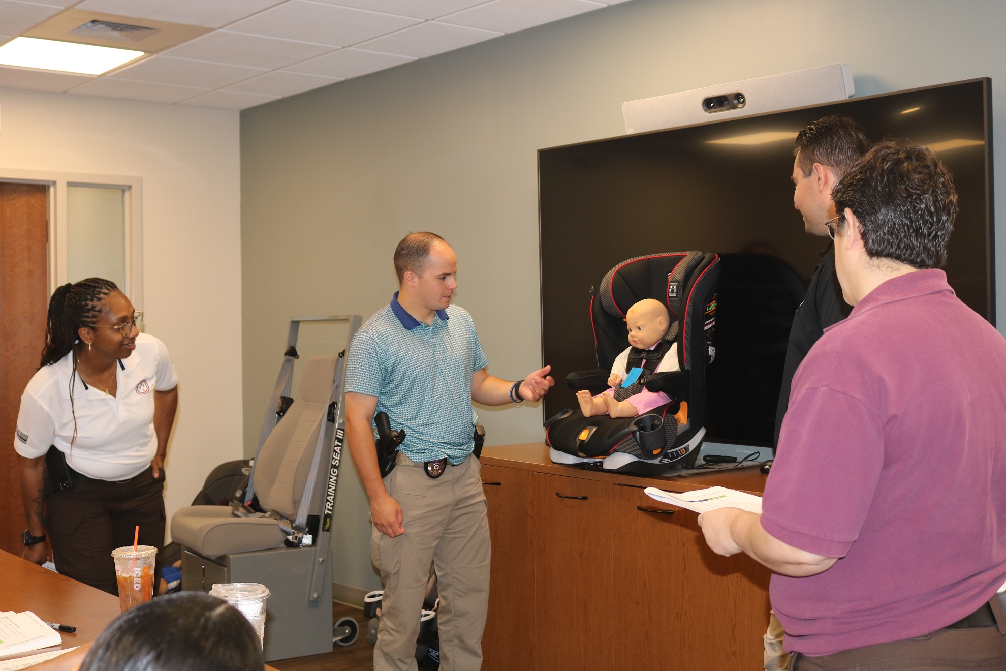 An instructor demonstrates proper seating for an infant doll in a car seat