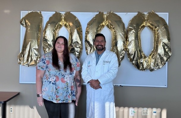 Donyelle Carmody stands with surgeon Neil Ghushe and a 1000th surgery balloon