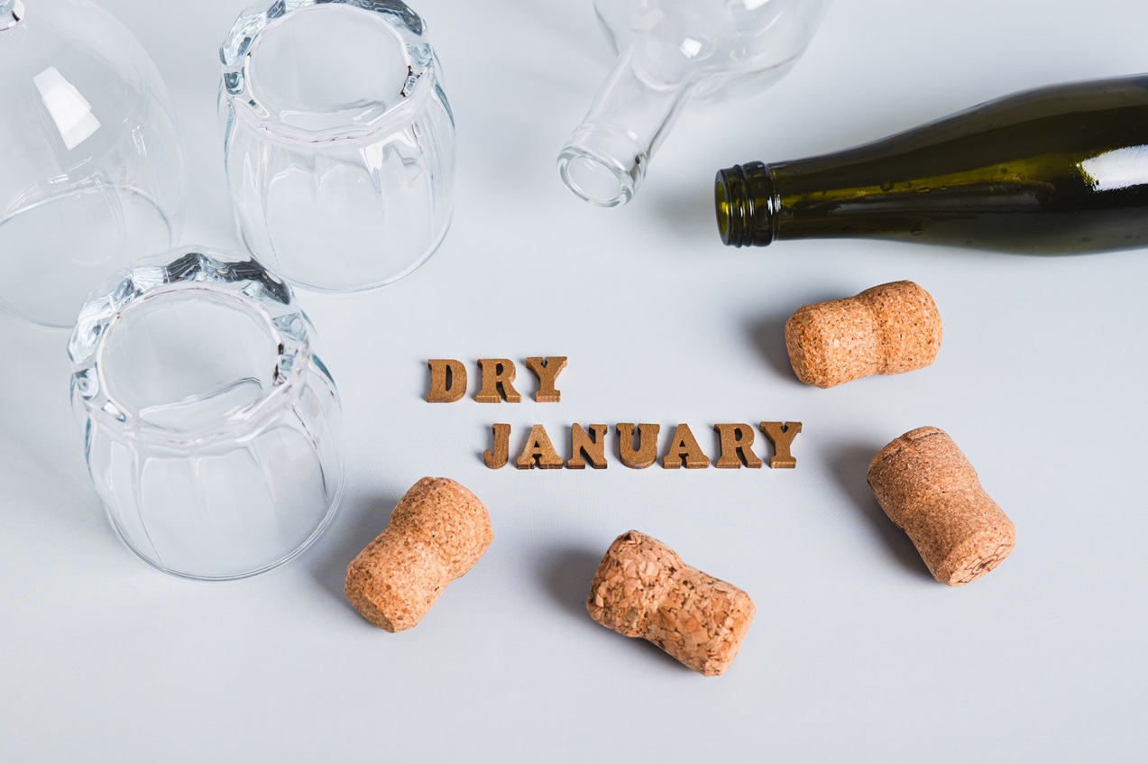 Dry January graphic with an empty wine bottle, corks and overturned glasses