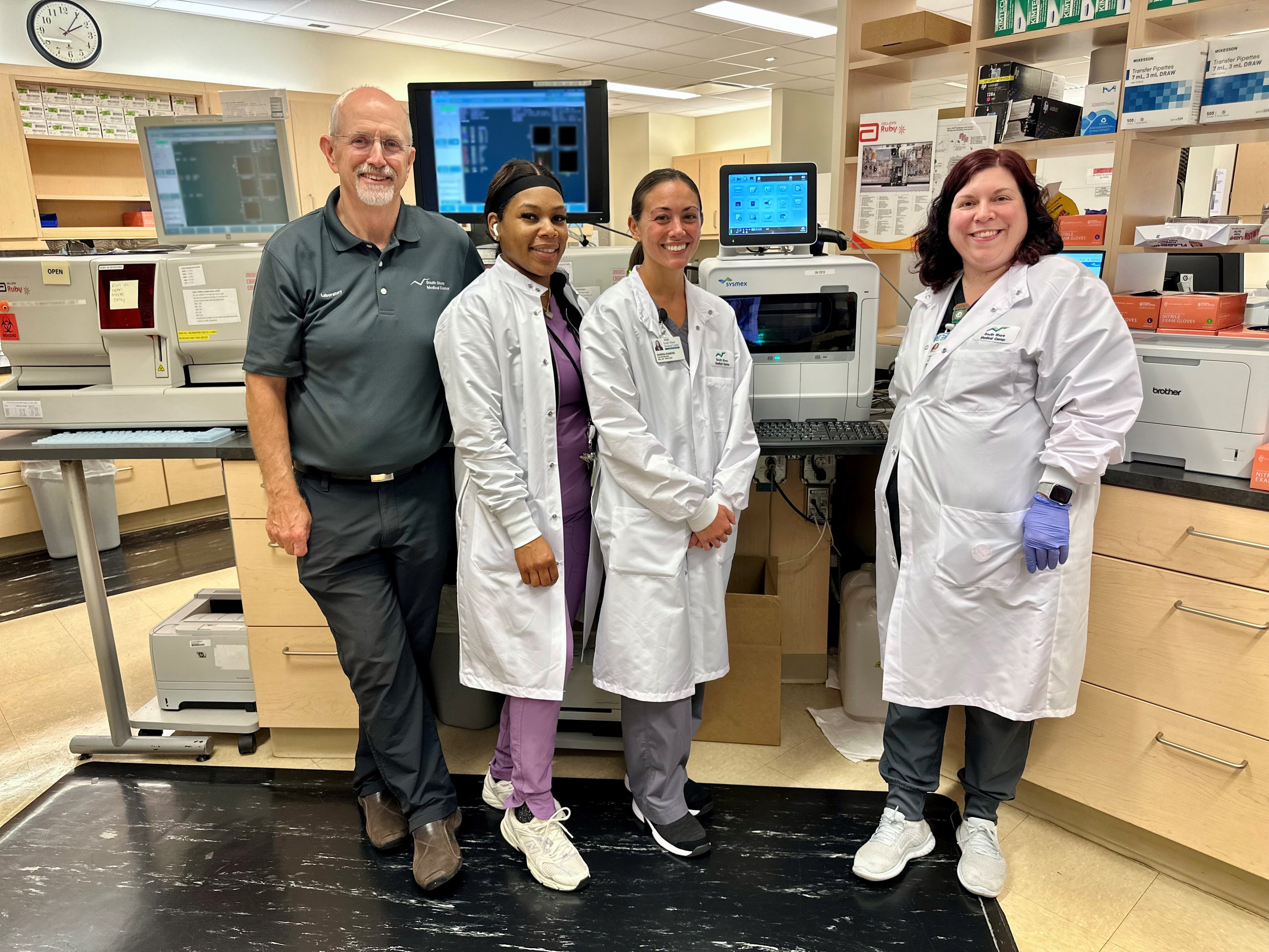 4 colleagues from South Shore Medical pose for a photo in front of the new Sysmex analyzer.