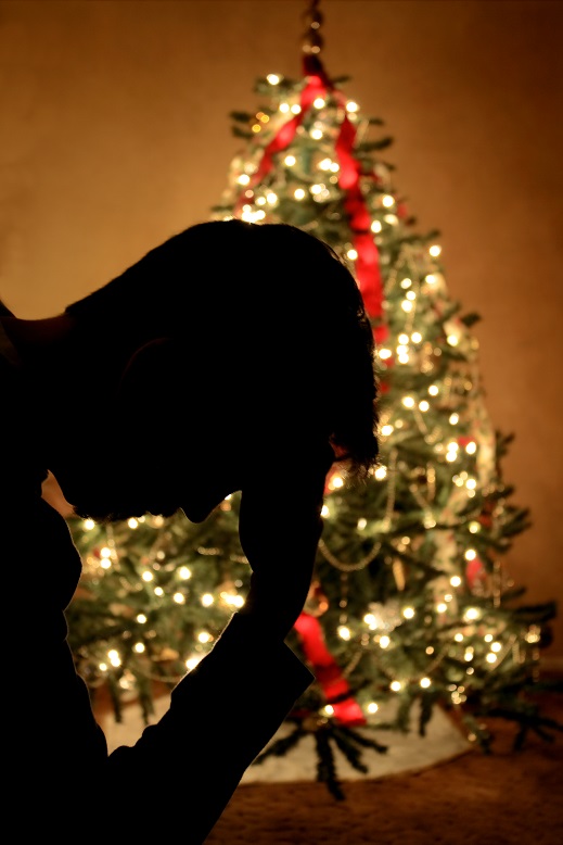 Man holding head in front of Christmas tree