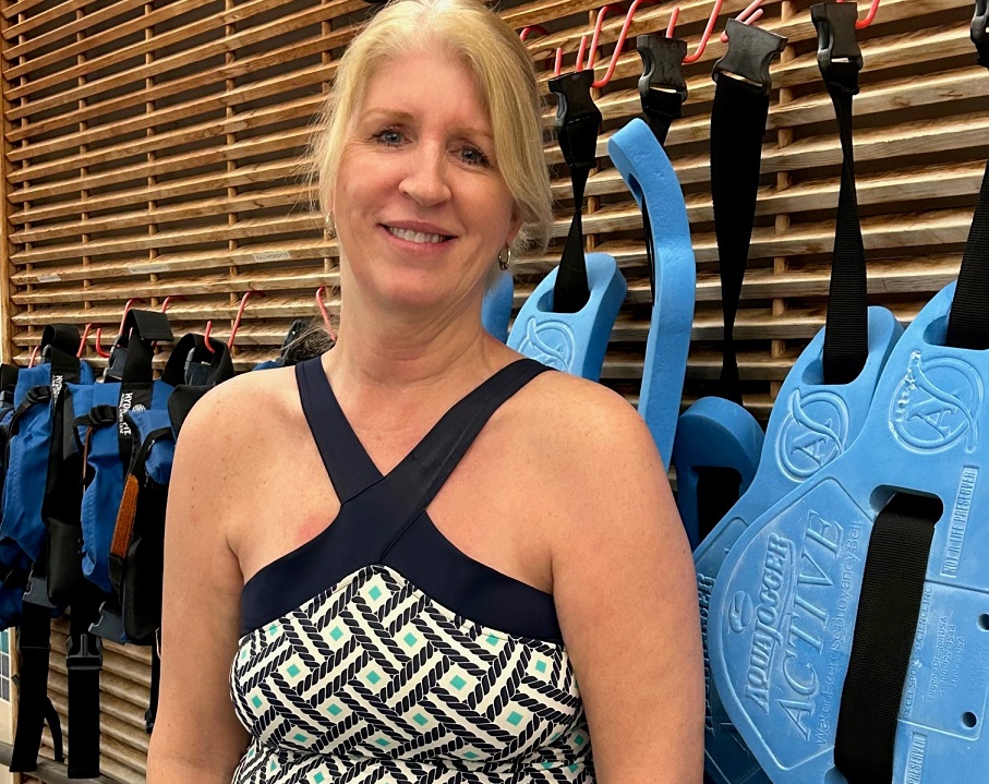 A woman in a bathing suit posing before pool class.