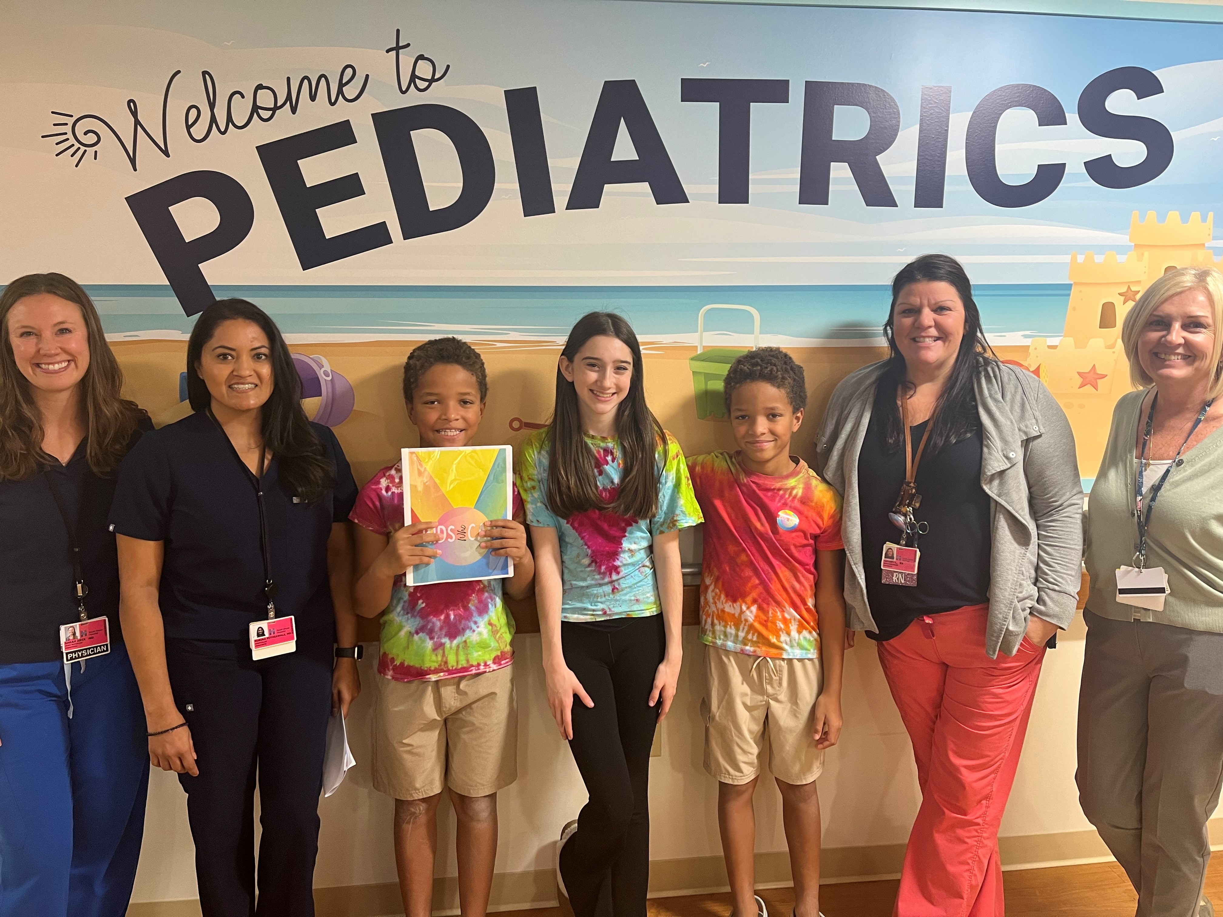 Kids from Kids Who Care pose for a photo with members of South Shore Hospital's Pediatrics Unit
