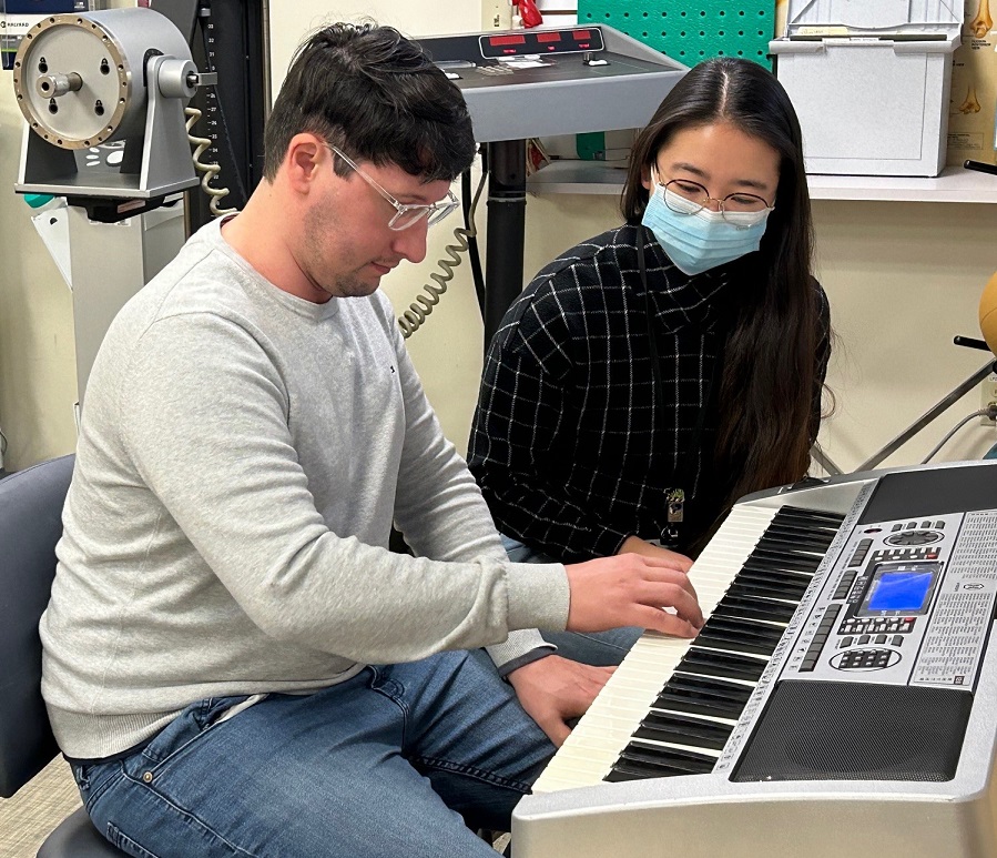 A male rehab patient plays piano as a female occupational therapist watches