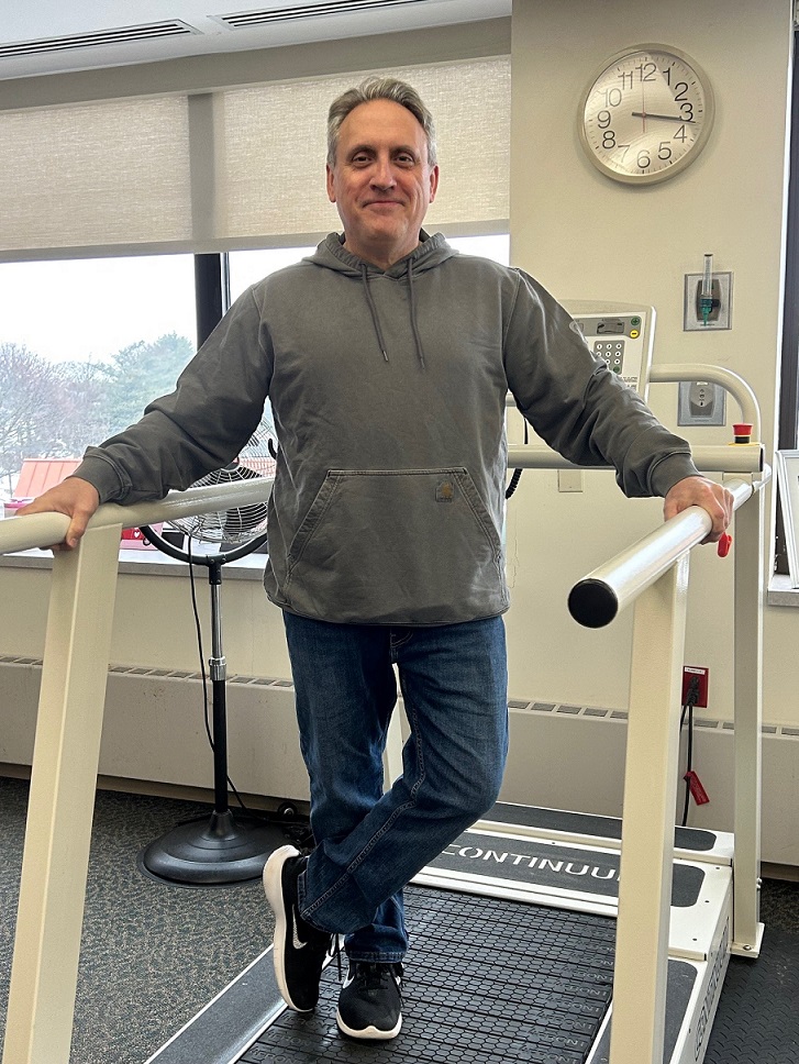 A male cardiac rehab patient poses for a photo on a treadmill