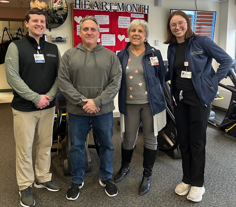 Cardiac rehab staff pose for photo with a male patient
