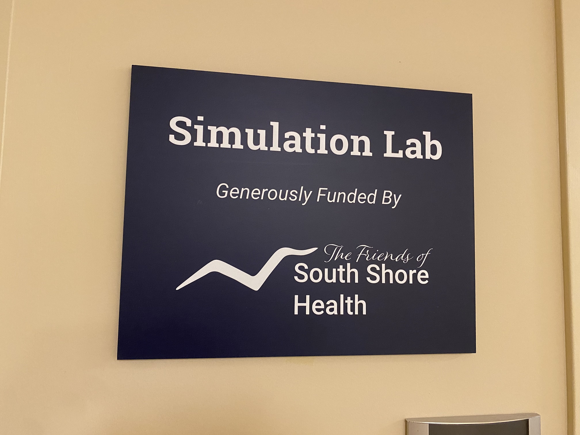 Blue wall sign reading "Simulation Lab generously funded by The Friends of South Shore Health"