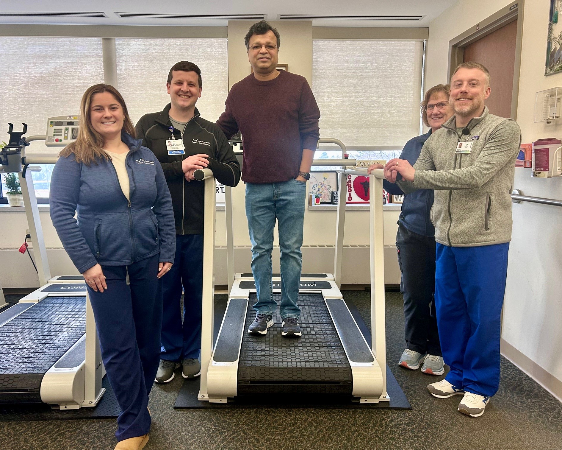 Sanjay Padhi standing on a treadmill surrounded by his cardiac rehab team