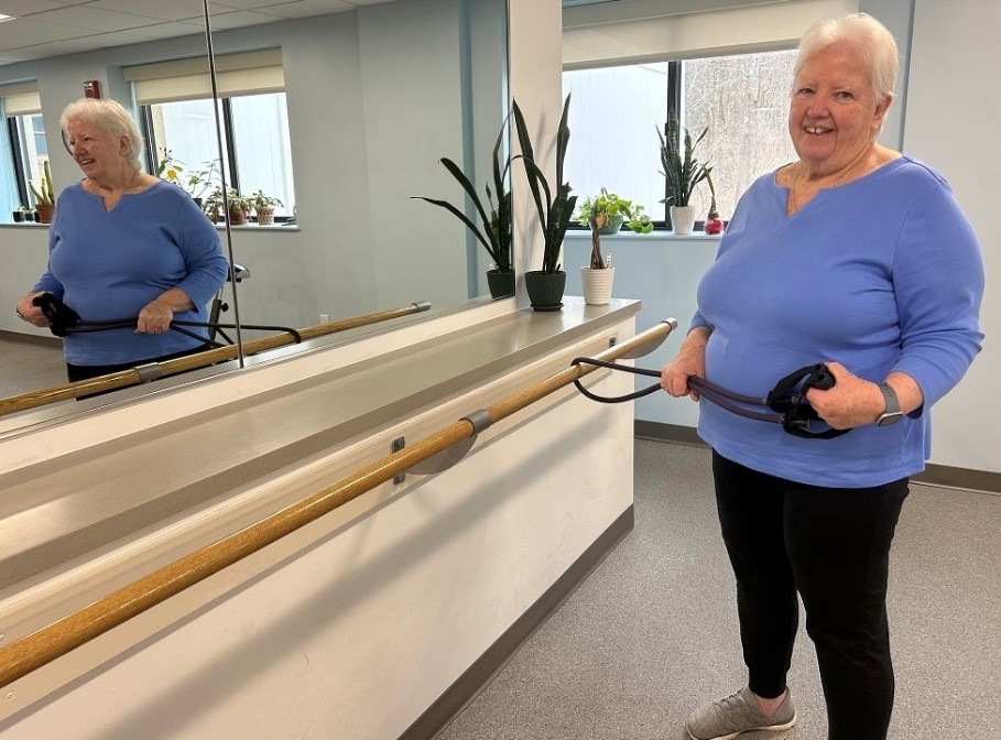 Sue Cullinan poses for a photo by the mirror in the senior strength training class