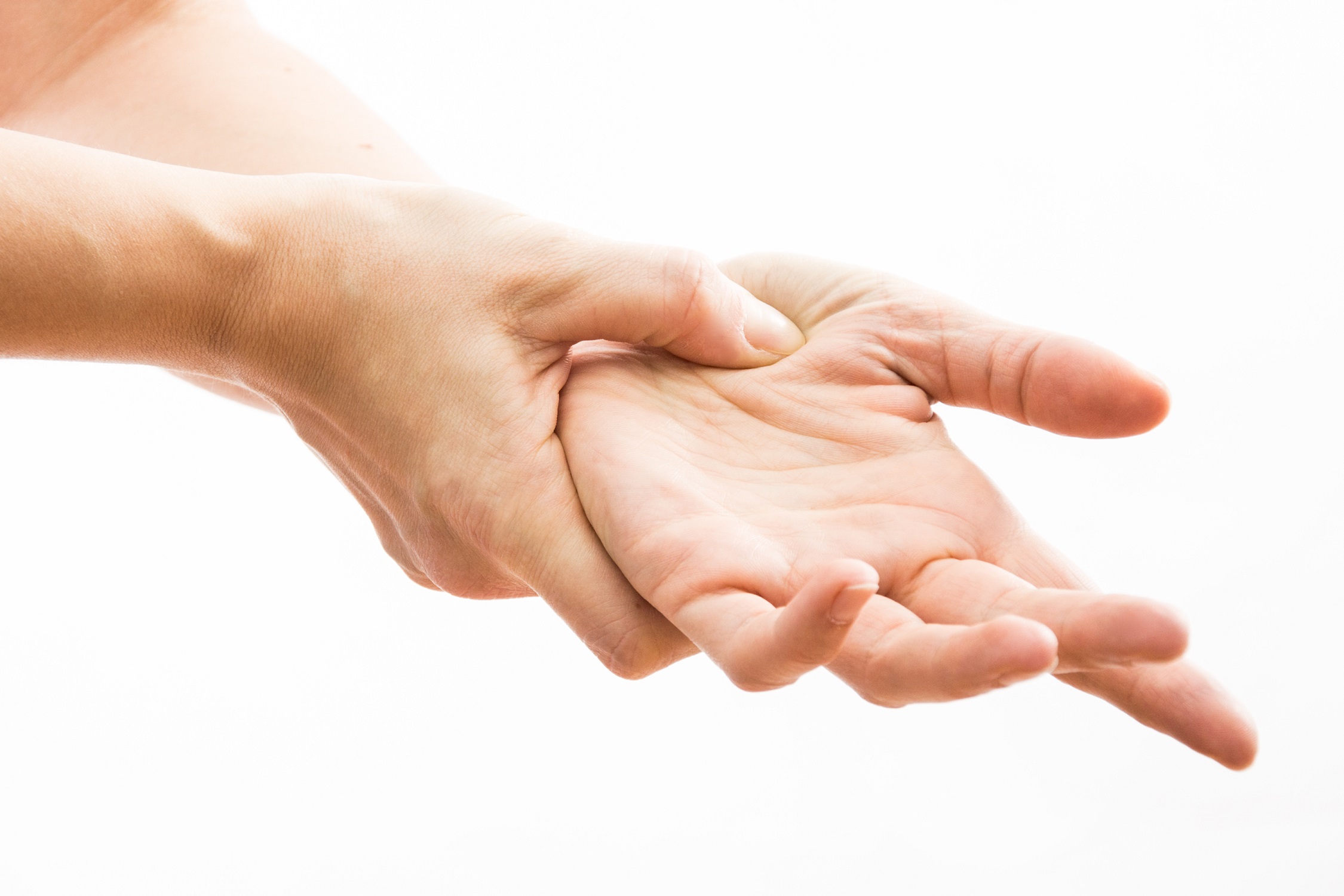 Close-up view of a woman's hands as she uses her right hand to apply acupressure to her left palm