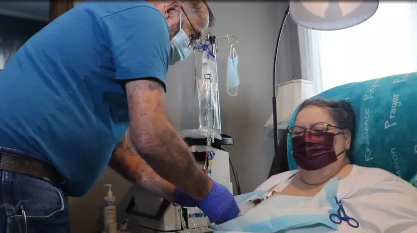 Bill Barns prepares his wife Gigi for a home dialysis treatment.
