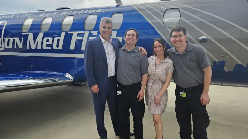 Todd Ellerin and other colleagues from South Shore Health post for a photo next to a Boston MedFlight airplane at the Convoy of Champions parade.