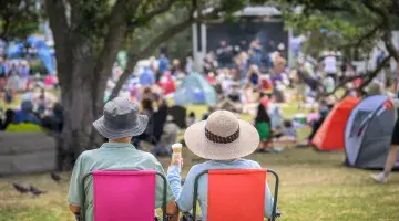 A back view of a couple seated in lawn chairs at an outdoor concert.