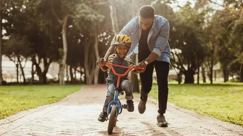 Dad helping son learn how to ride a bike
