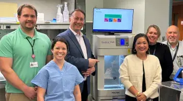 Six colleagues from South Shore Health, The Friends, and the Cancer Center pose next to a donated Faxitron machine.