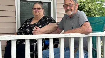 Georgeanne and Bill Barnes holding hands sitting on their porch