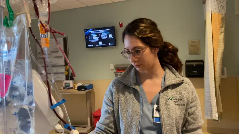 Photo of KT, a nurse at South Shore Hospital's Critical Care Unit, checking an IV bag