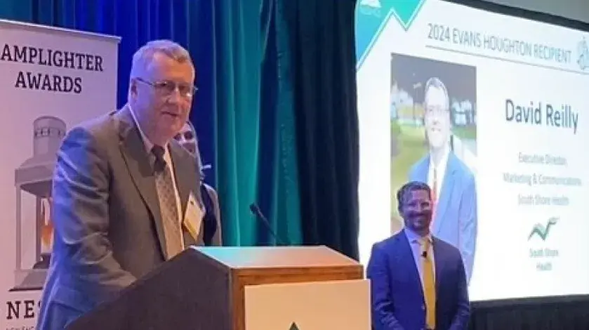 David Reilly of South Shore Health stands at the podium after receiving the Evans F. Houghton Award at the 2024 NESHCo conference.