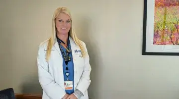 A photo of Rebecca Graziano, CNP of South Shore Hospital, wearing a white lab coat and scrubs.