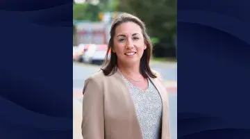 A professional headshot of Sasha Griffith, CRNA on a navy patterned background.