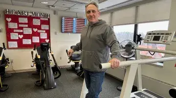 A cardiac rehab patient standing on a treadmill for photo