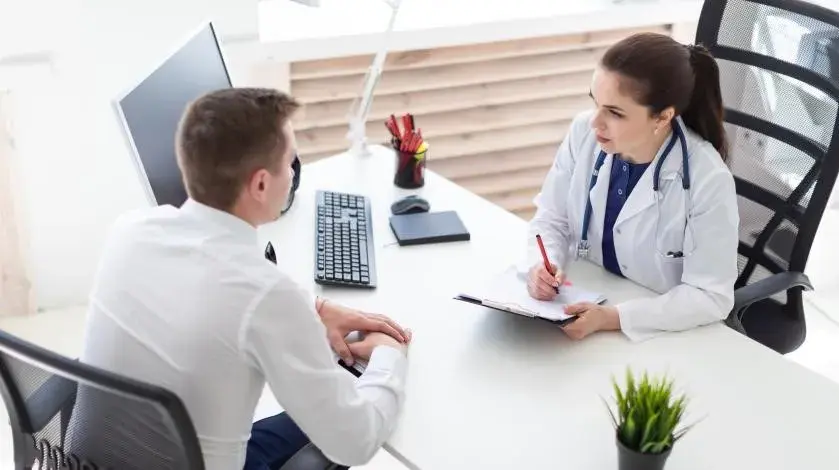 A young male patient consults with female provider at a desk