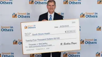 Thomas McCarthy holds an oversized donation check for $25,000 to South Shore Health at the Invest in Others Awards.