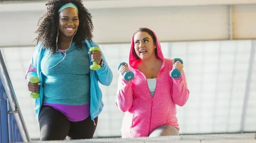 Two women walking together and carrying free weights